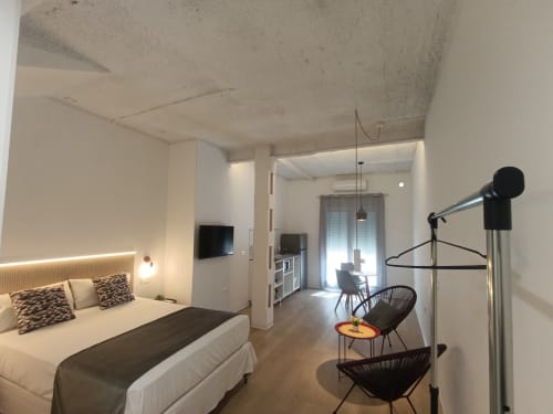 Dormitorio moderno en apartamento El Rincón de Sevilla con cama, TV, zona de descanso y cocina integrada en San Juan de Aznalfarache