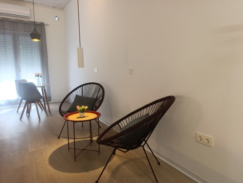 Sala moderna del apartamento El Rincón de Sevilla con sillas tejidas negras, mesa redonda amarilla y luz natural