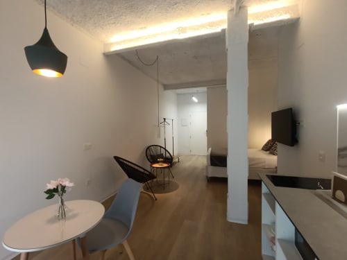 Sala de estar moderna con mesa de comedor, silla negra, luz colgante y cocina en San Juan de Aznalfarache