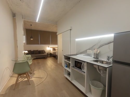 Cocina y sala de estar modernas en El Rincón de Sevilla con electrodomésticos de acero inoxidable y sofá confortable