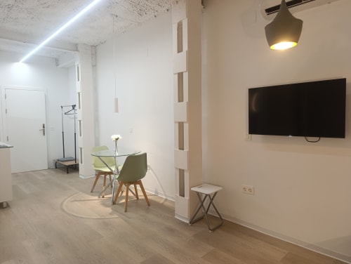 Sala de estar moderna con mesa de comedor de cristal, silla verde, TV montada en la pared y decoración minimalista en El Rincón de