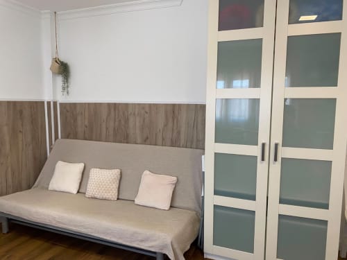 Sofá cama confortable con almohadas en el apartamento El Rincón II, Sevilla, armario con puertas de cristal visible