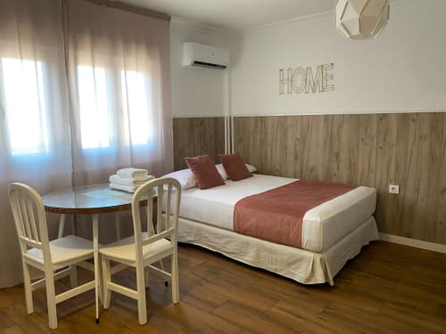 Moderna habitación en El Rincón de Sevilla con pared de madera, cama doble y vistas a la ciudad cerca del centro histórico de Sevilla