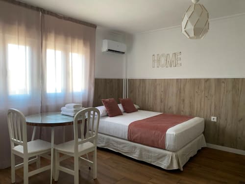 Habitación luminosa en El Rincón II de la Macarena en Sevilla con cama doble, escritorio, pared de madera y vistas a la ciudad