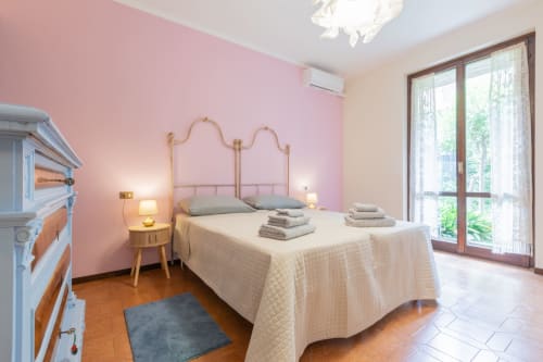 Camera luminosa al Prince Garda Salò con parete rosa, letto in metallo e balcone vista lago