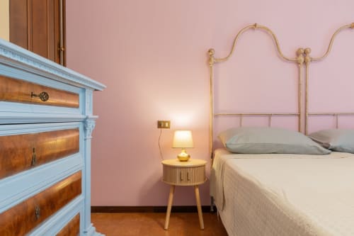 Camera elegante al Prince Garda hotel di Salò con pareti rosa, letto in ottone e cassettone in legno vintage