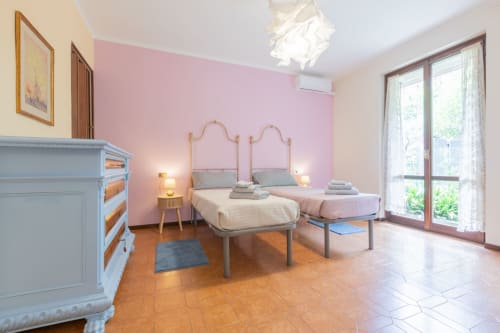 Camera rosa al Prince Garda Hotel di Salò con letti gemelli, pavimenti in terracotta e porte con vista sul lago