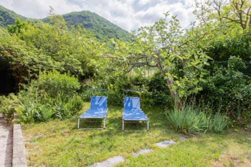Due lettini blu in un lussureggiante giardino dell'Hotel Prince Garda a Salò, con vista sulle montagne verdeggianti