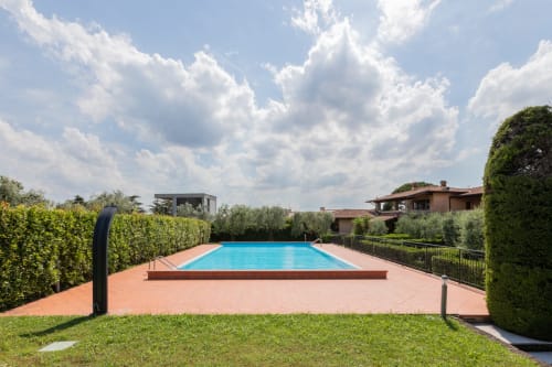 Piscina olimpionica dell'Hotel Prince Garda con patio in cotto, circondata da siepi e giardini a Salò