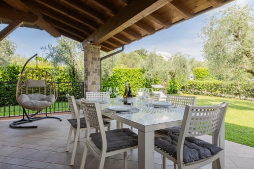 Elegante terrazza esterna dell'hotel Prince Garda a Salò con arredi bianchi, poltrona sospesa a uovo e vista sul lago