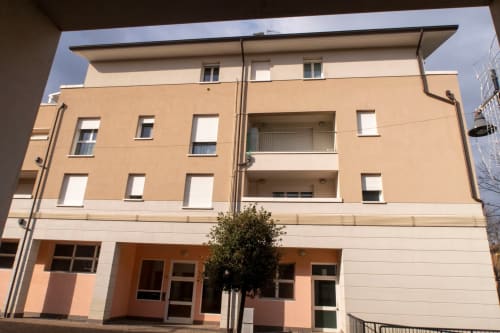 Casa di Cinti exterior in Pianoro, Italy - modern beige apartment building with balconies and ground floor entrance