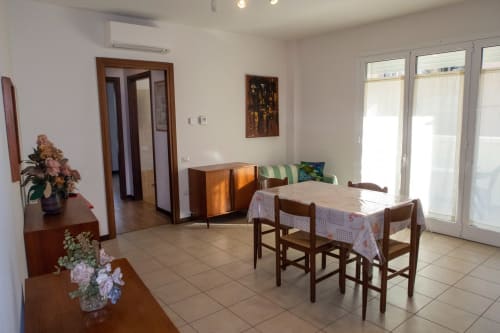 Bright living room in Esperanto apartment at Casa di Cinti with dining table, wooden furniture, and doors to courtyard view