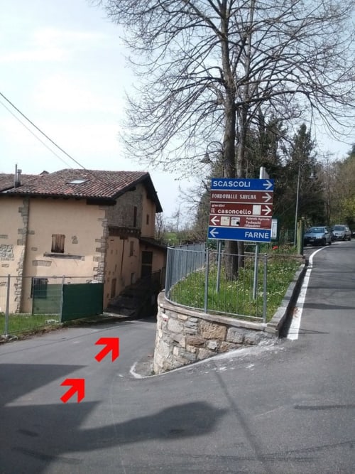 Casa di Cinti B&B entrance with directional signs in Italian countryside, red arrows marking driveway approach