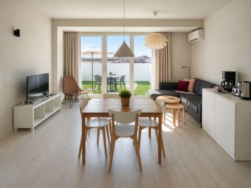 Suite moderna del hotel Holibai en Baiona con zona de comedor, sofá, vistas al mar y acceso a terraza