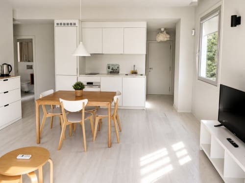 Cocina abierta moderna y zona de estar en Holibai, Baiona, con mesa de comedor de madera y muebles blancos