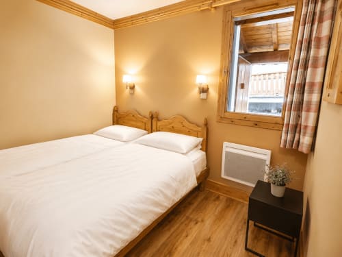 Chambre cosy du chalet Les étoiles de la plagne avec lit en bois, linge blanc et vue sur les montagnes à La Plagne Tarentaise