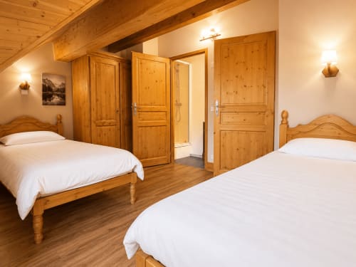 Chambre twin au Chalet du Vallon 19 aux Étoiles de la Plagne avec poutres apparentes et mobilier rustique en pin