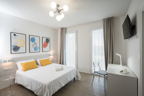 Camera matrimoniale moderna a Hotel Villa Mary con vista giardino, accenti gialli, opere d'arte astratta e arredi contemporanei