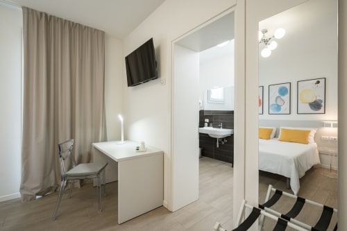 Camera moderna di Villa Mary con letto matrimoniale, scrivania, TV a schermo piatto, bagno e cuscini gialli a Santa Maria di