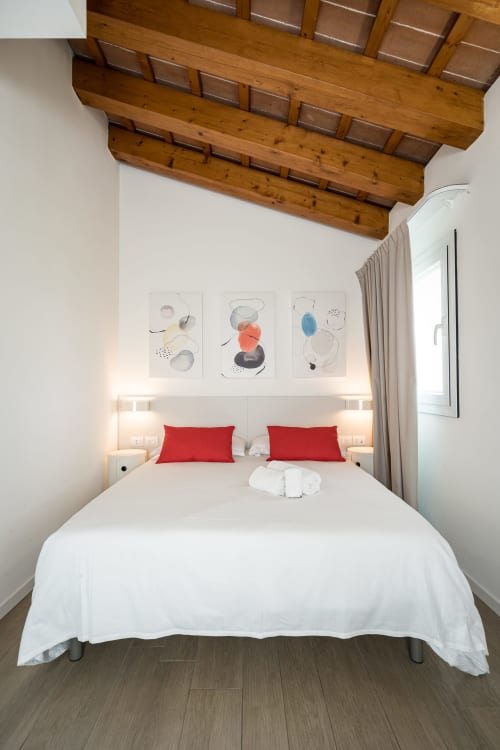 Camera moderna dell'Hotel Villa Mary con letto matrimoniale, cuscini rossi, travi in legno a vista e arte astratta a Santa Maria