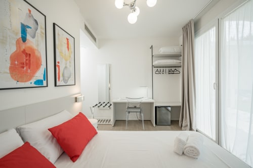 Camera moderna di Villa Mary con letto matrimoniale, cuscini rossi, opere d'arte astratta, zona scrivania e vista sul giardino a Santa Maria di