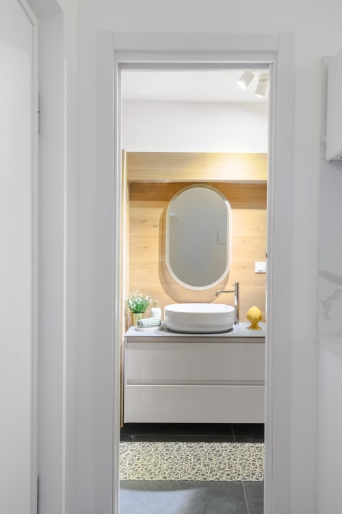 Bagno moderno nell'Almatros Yellow Apartment a Sulmona con specchio ovale, lavabo rotondo e parete in legno