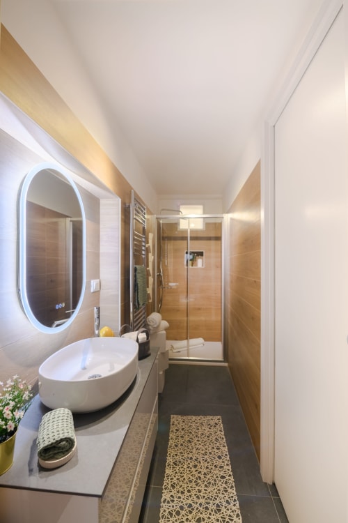 Bagno moderno dell'Appartamento Giallo presso l'hotel Almatros a Sulmona con specchio ovale, lavabo da appoggio e doccia walk-in