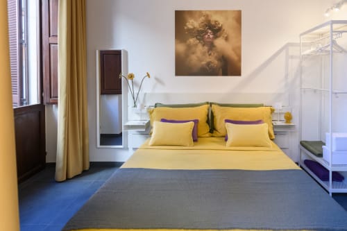 Camera da letto Yellow Apartment dell'hotel Almatros a Sulmona con biancheria gialla, testata verde e pavimento blu