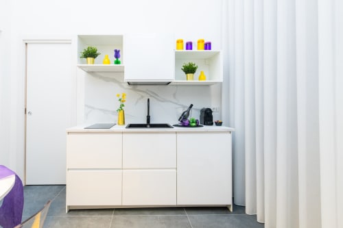 Angolo cottura moderno nell'Yellow Apartment dell'hotel Almatros a Sulmona, con mobili bianchi, rivestimento in marmo e accenti colorati