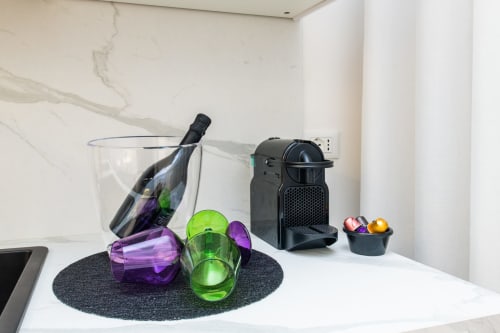 Moderno bancone della cucina dell'Almatros Yellow Apartment a Sulmona con macchina da caffè, bicchieri colorati e bottiglia di vino