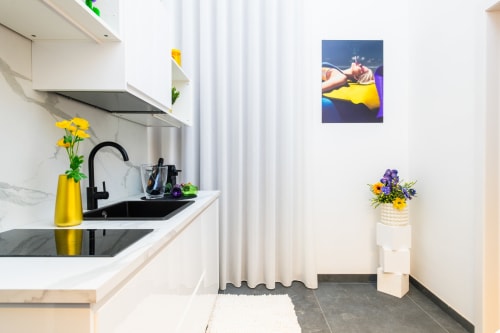 Cucina moderna nell'Appartamento Almatros Yellow a Sulmona, con fiori gialli, lavello nero, mobiletti bianchi e design contemporaneo