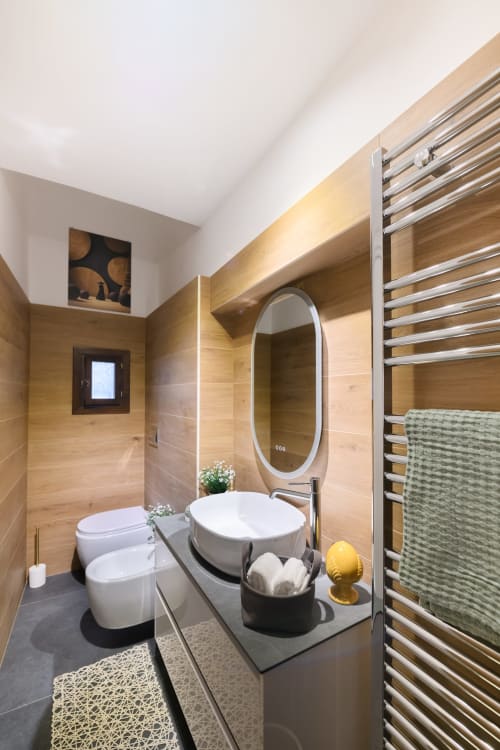 Bagno moderno nell'Almatros Yellow Apartment di Sulmona con rivestimento in legno, specchio ovale, lavabo bianco e scaldasalviette