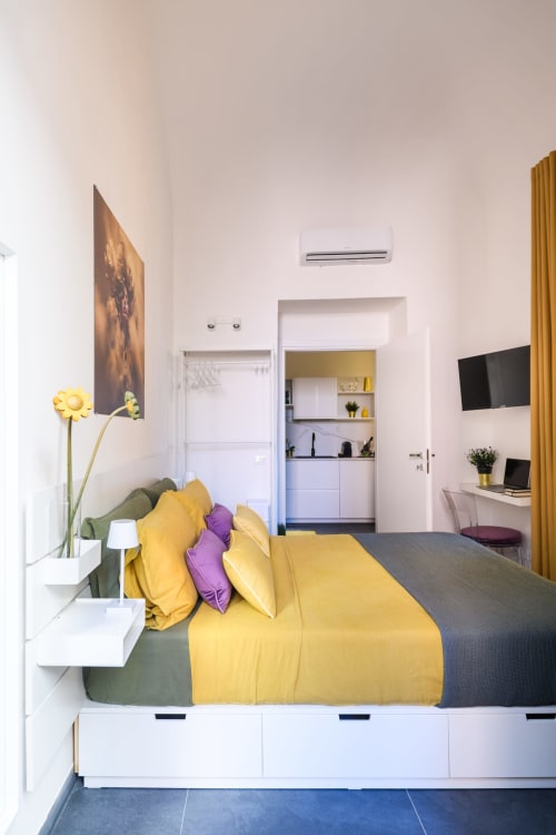 Camera da letto Yellow Apartment dell'hotel Almatros a Sulmona con biancheria colorata, angolo cottura e servizi moderni