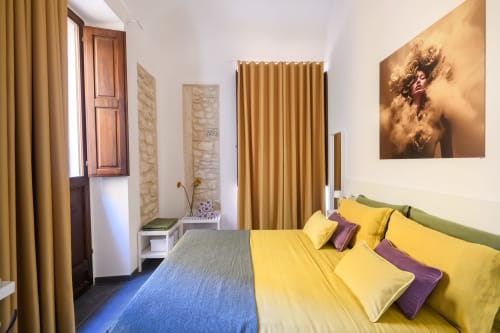 Camera Gialla dell'hotel Almatros a Sulmona con biancheria colorata, tende dorate e arredamento moderno