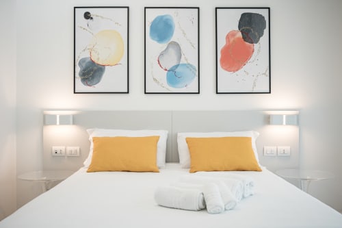 Camera moderna dell'Hotel Villa Mary con biancheria bianca, cuscini gialli e arte acquerello astratta sopra il letto a Santa