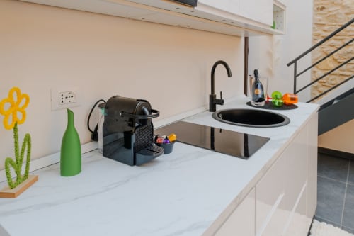Piano cucina moderno presso Almatros Green Apartment a Sulmona con marmo bianco, lavello nero, macchina da caffè e verde