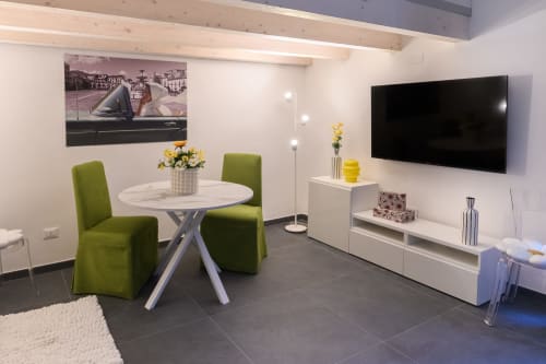 Appartamento Green dell'hotel Almatros a Sulmona con living moderno, tavolo rotondo, sedie verdi, TV e arredi bianchi