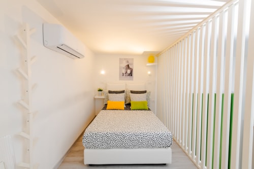 Camera moderna nell'Almatros Green Apartment di Sulmona con letto matrimoniale, dettagli gialli, ringhiere bianche e illuminazione calda