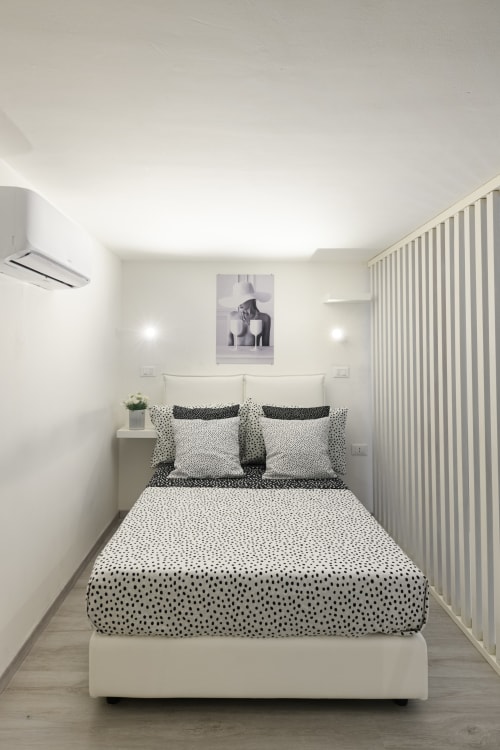 Camera moderna in Almatros Green Apartment a Sulmona con biancheria a pois, pareti bianche e arredi contemporanei