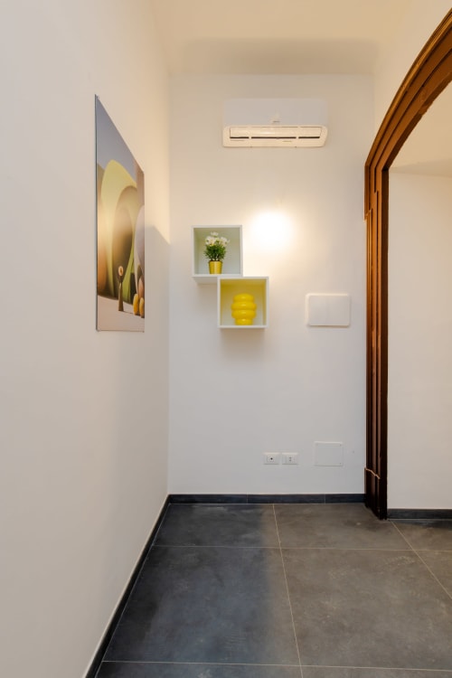 Ingresso moderno dell'Aparthotel Green ad Almatros a Sulmona con scaffali bianchi, dettagli gialli e pavimento in scuro