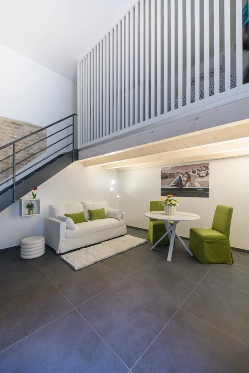 Lounge moderno con design verde dell'hotel Almatros a Sulmona: divano bianco, sedie lime e soppalco