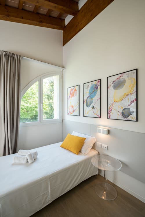 Camera singola con vista giardino all'Hotel Villa Mary, con letto, cuscino giallo, finestra ad arco e quadri colorati