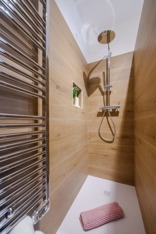 Doccia moderna nell'Appartamento Peonia dell'hotel Almatros a Sulmona, con pareti in piastrelle in legno e soffione a pioggia