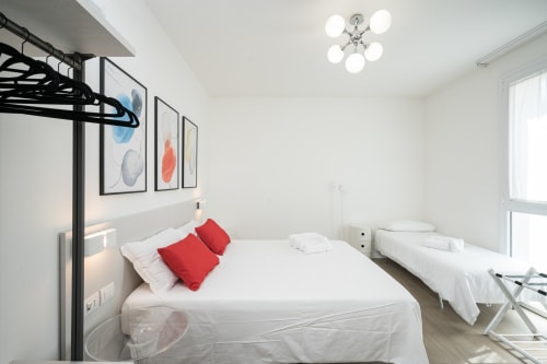 Camera tripla all'Hotel Villa Mary con letto a soppalco, cuscini rossi, letto singolo, arredamento bianco moderno e arte murale astratta a Santa