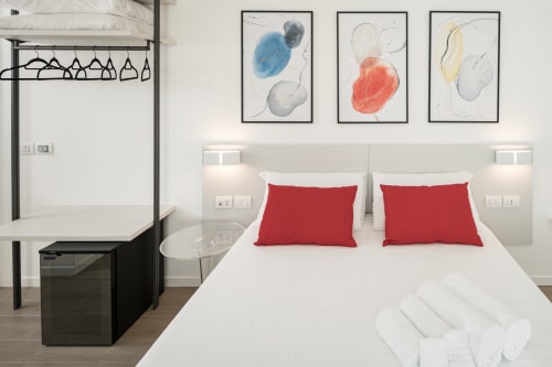 Camera moderna di Villa Mary con letto matrimoniale, cuscini rossi, biancheria bianca, scrivania e arte astratta alle pareti a Santa Maria di