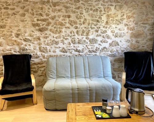 Acogedor rincón de descanso en La suite de la citadelle del Au Château De Villelongue, con muros de piedra y muebles tapizados