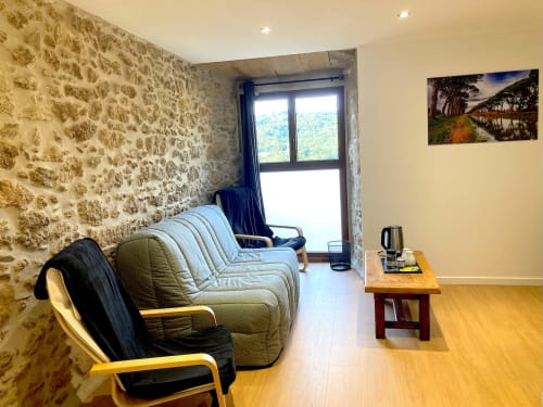 Suite espaciosa en Au Château De Villelongue con muros de piedra, cómodos asientos, vistas a las montañas y comodidades modernas