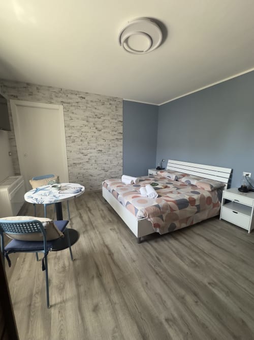 Camera moderna al Casale Rusignûl con letto bianco, parete blu, carta da parati in mattoni e pavimento in legno