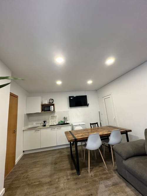 Modern hostel room at Vila Alexandra, Costa da Caparica with kitchenette, dining table, TV, and comfortable seating