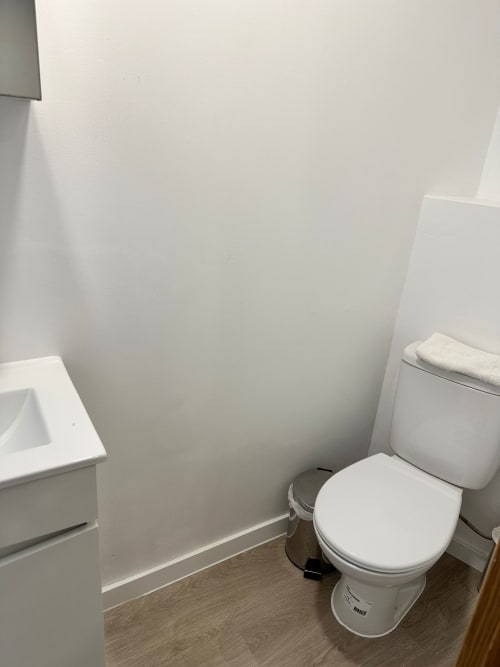 Clean bathroom at Vila Alexandra hostel in Costa da Caparica with white toilet, sink, and tiled flooring